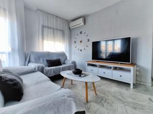 a living room with a tv and a couch and a table at Apartamento y Parking en pleno CENTRO, DAMAS in Huelva