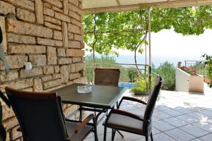 a table and chairs on a patio with a stone wall at Rato in Murter