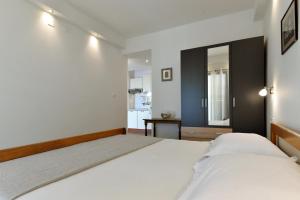 a bedroom with two white beds and a kitchen at Rato in Murter