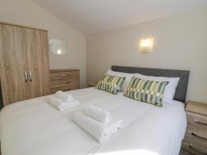 a bedroom with a white bed with towels on it at Y Caban in Cemaes Bay