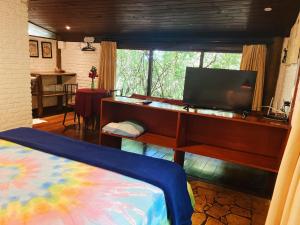 a bedroom with a desk with a television and a bed at Chalés Mirante de Pipa in Pipa