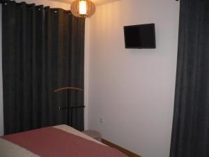 a room with a tv on the wall and a curtain at Maria João in Paredes de Coura