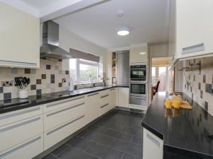 a kitchen with white cabinets and black counter tops at Kingsford House in Ross on Wye