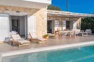 um pátio com uma mesa e cadeiras ao lado de uma piscina em Fiscardo Luxury Stone Villa Suzana ,with sunset view! em Fiskardo