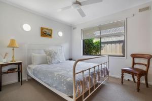 a bedroom with a bed and a chair and a window at Scotshaven in Port Fairy