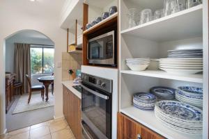 a kitchen with a microwave and plates on shelves at Scotshaven in Port Fairy