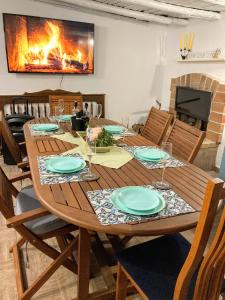 een houten eettafel met stoelen en een open haard bij Къща за гости ЗЕЛЕНА in Vinogradets