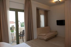 a bedroom with a bed and a chair and a window at Aphrodite Samos Suites in Marathokampos
