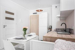 a small white kitchen with a white table and chairs at Ślusarska Apartment 2 in Krakow