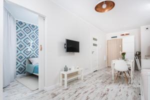 克拉科夫的住宿－Ślusarska Apartment 2，白色的客房设有书桌和墙上的电视。
