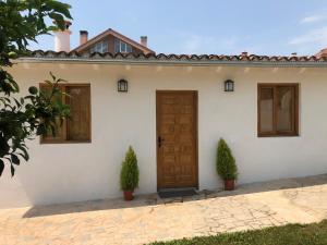 een wit huis met een houten deur en twee planten bij La casita de El Montán in Avilés