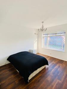 a bedroom with a black bed and a window at Cozy & Quiet Two Bedroom Apartment in Chingford