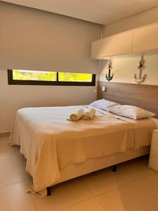 a bedroom with a bed with two towels on it at Oka Flat Muro Alto in Porto De Galinhas