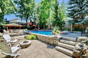 un patio trasero con una piscina con sillas y una mesa en Cheerful 7 bedrooms Villa with Hot tub & Pool. en Mississauga