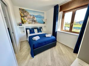een slaapkamer met een bed met blauwe lakens en een raam bij La Maison Du Soleil in Agerola