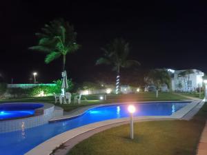 a swimming pool at night with palm trees at Sonia Flats Tabatinga - Flat térreo em condominio à beira mar in Nísia Floresta