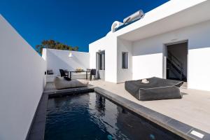 a pool in the backyard of a white house at Filoxenia Luxury Villas in Perissa