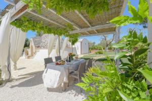 Una mesa debajo de una pérgola con una mesa y sillas. en TRULLO CHEFMARCO PRIVATE/SALTWATER SWIMMING POOL, en San Michele Salentino