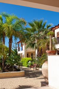un patio con palmeras, un banco y un edificio en Residence Casa Del Mar Sicilia, en Marina di Modica