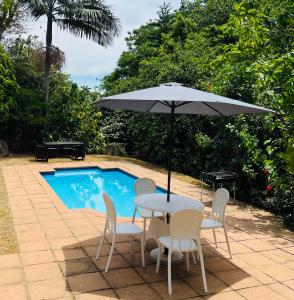 stół i krzesła z parasolem przy basenie w obiekcie Modern Luxury 3 bedroom house w mieście Durban