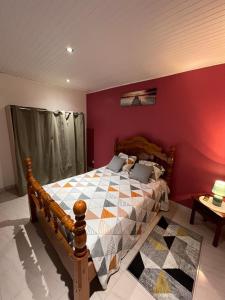 Schlafzimmer mit einem Holzbett mit einer roten Wand in der Unterkunft Poseidon in Le Lamentin