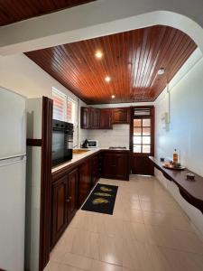 eine Küche mit Holzschränken und einem weißen Kühlschrank in der Unterkunft Poseidon in Le Lamentin