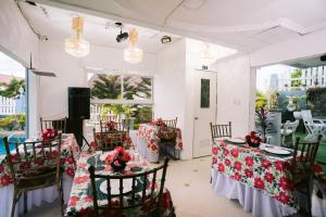 Balanga的住宿－Grand Peninsula Suites，用餐室配有2张桌子和椅子,并装饰有红色的鲜花
