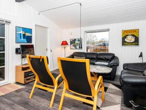 ein Wohnzimmer mit einem Sofa, einem Tisch und Stühlen in der Unterkunft Holiday home Ulfborg XXVII in Ulfborg