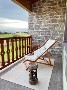 a rocking chair on a porch with a stone wall at Alto el Monte 2 - AR1414 in Bocines