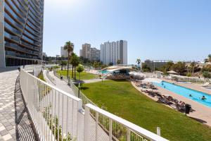 a view of a pool with people sitting on the grass at SUNSET WAVES superb apartments in Benidorm