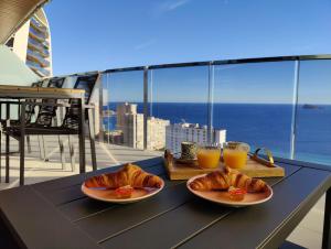 a table with two plates of croissants and two glasses of orange juice at SUNSET WAVES superb apartments in Benidorm