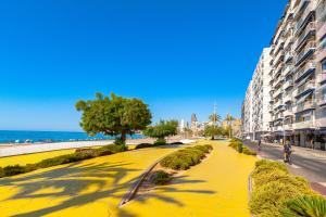 a walkway next to a beach with a building at SUNSET WAVES superb apartments in Benidorm