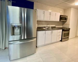 a kitchen with a stainless steel refrigerator and white cabinets at Centric 3B/1Bath near trendy Loiza Street in San Juan