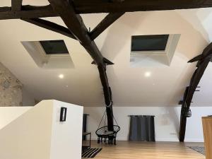 Le Loft Gîte de Dordogne في Mussidan: غرفة مع عوارض خشبية وتلفزيون على السقف