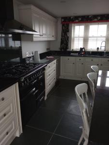 a kitchen with white cabinets and a stove top oven at Quayside in Porthscatho