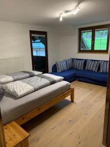 ein Wohnzimmer mit 2 Betten und einem blauen Sofa in der Unterkunft Ferienwohnung Schmaranzer in Gosau
