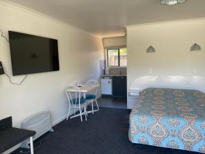 a hotel room with a bed and a flat screen tv at Blue Seas Motel in Kaikoura