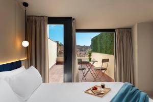 a hotel room with a bed and a view of a balcony at Coeo Apart-Hotel Peña in Málaga