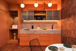 a kitchen with orange cabinets and a table and chairs at Coeo Apart-Hotel Peña in Málaga