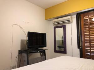 1 dormitorio con cama, TV y espejo en Departamento de un dormitorio en pleno centro de Carlos Paz en Villa Carlos Paz