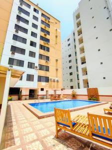 a swimming pool with two benches and two tall buildings at Hermoso departamento con vista la playa murciélago in Manta