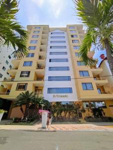 a large yellow building with palm trees in front of it at Hermoso departamento con vista la playa murciélago in Manta +41 photos