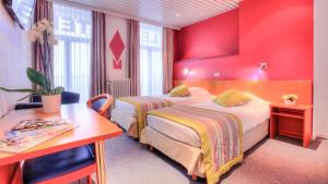 two beds in a hotel room with red walls at Hotel Le Terminus in Mons