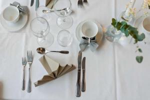 einen weißen Tisch mit silbernen Utensilien, Tellern und Gabeln in der Unterkunft Best Western Hotel Vrigstad in Vrigstad