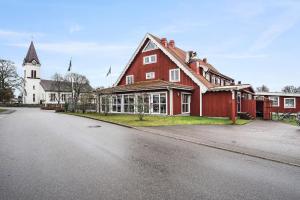 une grande maison rouge avec une église et une rue dans l'établissement Best Western Hotel Vrigstad, à Vrigstad