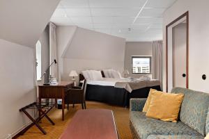 a hotel room with a bed and a couch and a table at Best Western Plus Grand Hotel in Halmstad