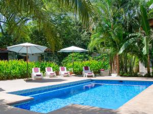 a swimming pool with two chairs and two umbrellas at Tamarindo Blue Apartments in Tamarindo