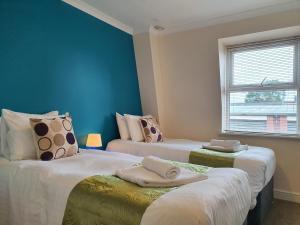 Dos camas en una habitación con paredes azules. en Old Town Apartments, en Swindon