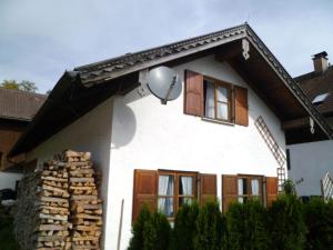 ein weißes Haus mit Holzfenstern und Sat-TV in der Unterkunft Delightful Holiday Home in Unterammergau with Terrace in Unterammergau