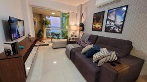 a living room with a couch and a television at Meu Resort no Recreio - RJ in Rio de Janeiro
